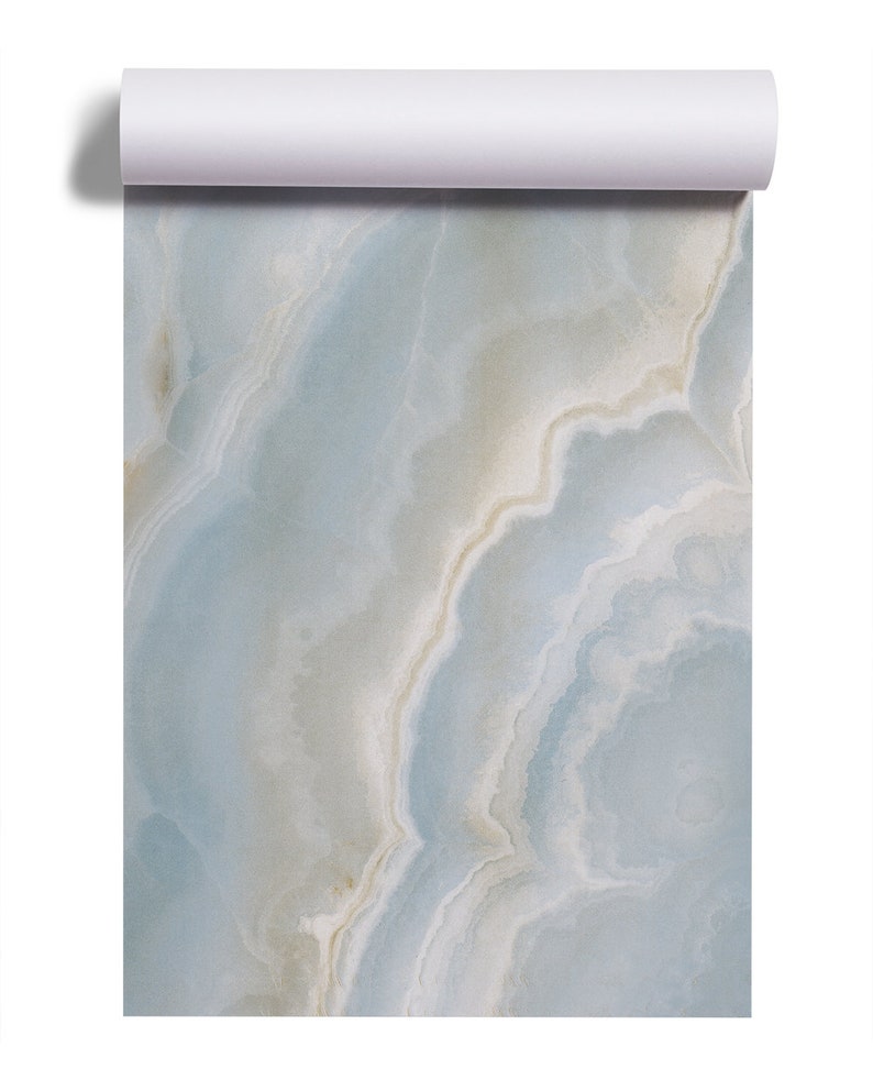 May include: A close-up of a blue and white marble wallpaper roll. The marble has a swirling pattern with shades of light blue, white, and beige.