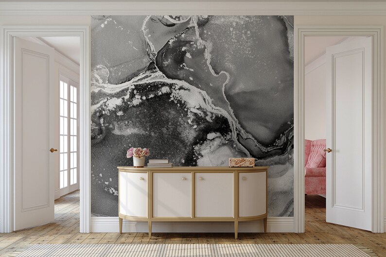 May include: A white cabinet with gold trim and four doors sits in front of a wall with a black and white abstract marble pattern wallpaper.