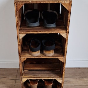 May include: A rustic, wooden shoe rack with three shelves. The rack is made from reclaimed wood, with a dark brown finish. The shelves hold various pairs of shoes, including sandals and heels. The rack is designed to be a space-saving storage solution.
