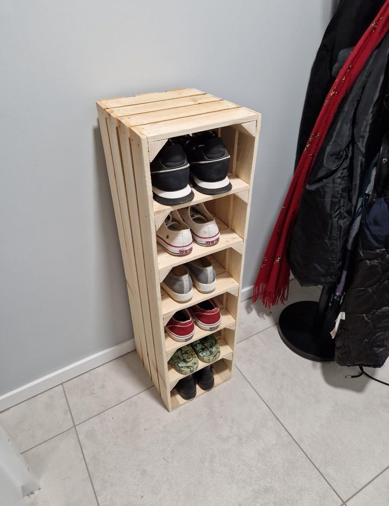 May include: A wooden shoe rack with multiple shelves, holding various pairs of shoes. The rack is made from light-colored wood and has a rustic, handmade appearance. The shoes include sneakers, flats, and other casual footwear.