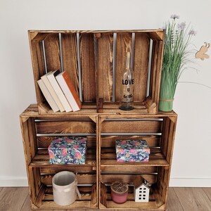 May include: Wooden crate shelves with various decorative items. The shelves hold books, floral patterned boxes, a bottle with the text "LOVE U to the", a candle, a small house, and a plant.