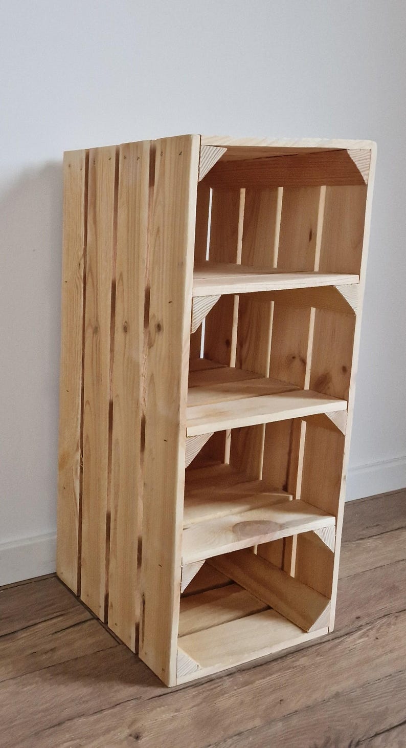 Puede incluir: Una unidad de almacenamiento alta y rectangular construida con listones de madera natural de color claro. La estructura cuenta con tres estantes abiertos con soportes de esquina reforzados, creando un dise&ntilde;o vertical tipo caja con veta de madera visible.