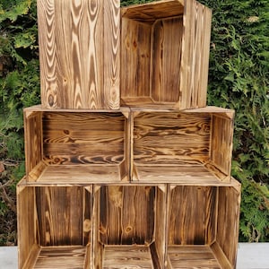 May include: A set of six wooden storage boxes stacked in a pyramid shape. The boxes are made of natural wood with a rustic, burnt finish. Each box has a square shape and is open on the top.
