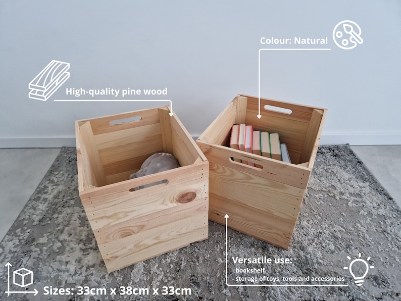 May include: Two natural wood storage crates with handles. The crate on the left is empty and the crate on the right is filled with books. The crates are 33 cm x 38 cm x 33 cm.  The text on the image reads: "High-quality pine wood", "Colour: Natural", "Sizes: 33cm x 38cm x 33cm", "Versatile use: bookshelf, storage of toys, tools and accessories".