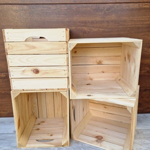 May include: Four wooden crates stacked in a staggered formation. The crates are made of natural wood and have a rustic appearance.