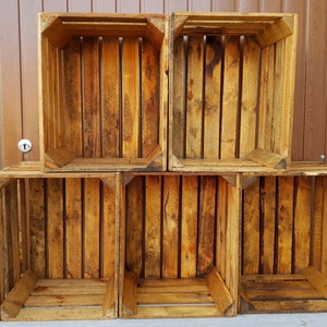 May include: Six wooden crates stacked in two rows. The crates are made of natural wood with a rustic finish. The crates are empty and ready to be used for storage or display.