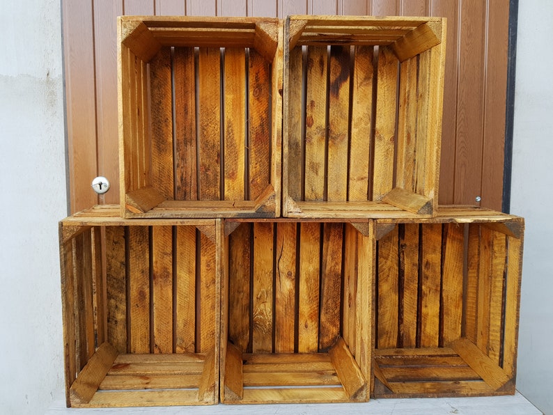 May include: Six wooden crates stacked in two rows. The crates are made of natural wood with a rustic finish. The crates are empty and ready to be used for storage or display.
