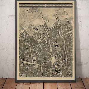 May include: A vintage black and white map of London, England. The map shows the city's streets and landmarks, including the River Thames, Westminster Abbey, and the Tower of London. The map is framed in a black frame.
