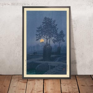 May include: A Japanese woodblock print depicting a moonlit scene with three trees silhouetted against a dark blue sky. The moon is a bright yellow circle in the upper left corner of the image. The trees are in the center of the image and are surrounded by a dark blue forest. The print is framed in a black frame.