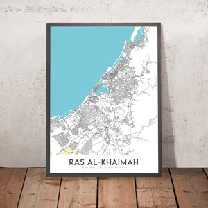 May include: A black and white map of Ras Al Khaimah, United Arab Emirates, with a blue and yellow colour scheme. The map shows the city's streets, roads, and coastline.