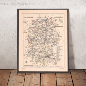 Puede incluir: Un mapa vintage de Wiltshire, Inglaterra, impreso en negro, rojo, verde y azul. El mapa muestra los límites del condado, las ciudades y los ríos. El título "Wiltshire" está impreso en letras grandes y negritas en la parte superior del mapa.
