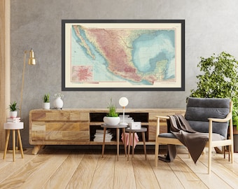 May include: A vintage map of Mexico in a black frame hangs above a wooden entertainment center with a gray armchair and a potted plant.