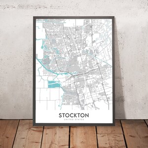 Op de afbeelding: Een zwart-witte kaart van Stockton, Californië, met blauwe waterkenmerken. De kaart is ingelijst in een zwart frame en de tekst "Stockton, Verenigde Staten" is onder de kaart gedrukt.