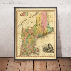 Pode incluir: Mapa vintage emoldurado dos estados da Nova Inglaterra, incluindo Maine, New Hampshire, Vermont, Massachusetts, Rhode Island e Connecticut. O mapa apresenta divisões coloridas dos condados e um fundo creme. A moldura é cinza escuro.