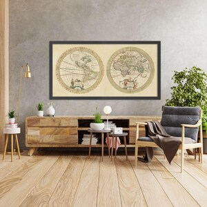 May include: A vintage world map print in a black frame hangs on a gray wall above a wooden console table. The map is in a circular format and shows the continents of the world. The console table is made of wood and has a light brown finish. There are plants and a lamp on the table. A gray armchair with a brown throw blanket sits in front of the table.
