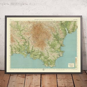 May include: A vintage map of England and Wales, printed on paper with a cream background. The map shows the terrain with green and brown colors. The map is framed in a black frame.
