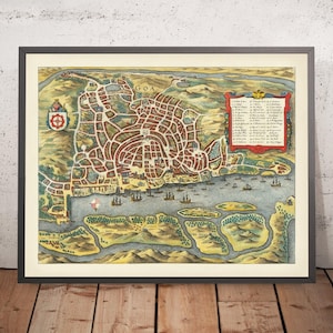 May include: Framed vintage map of Goa, India, featuring a detailed city plan with red and brown buildings, green landscapes, and blue water. The map includes text, a coat of arms, and sailing ships. The frame is black.