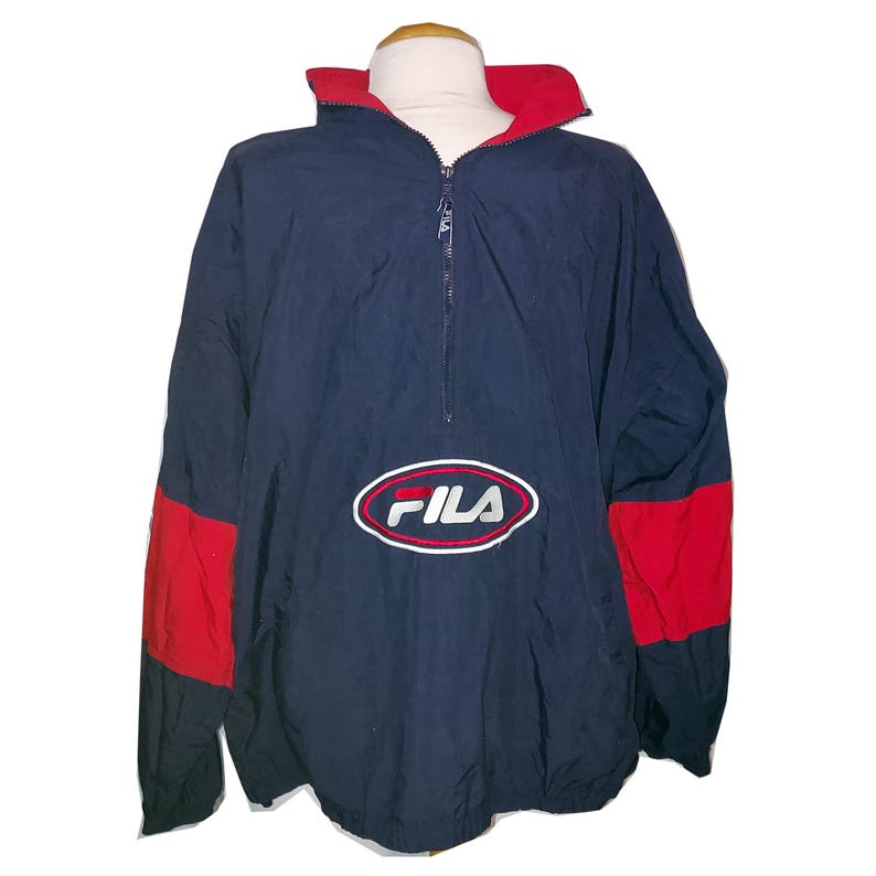 Pu&ograve; includere: Giacca Fila blu navy e rossa. La giacca presenta un colletto rosso e pannelli rossi sulle maniche. Il logo Fila &egrave; ricamato sul davanti. Presenta una chiusura a mezza zip.