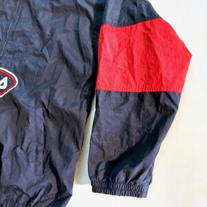 Pu&ograve; includere: Giacca sportiva blu navy e rossa con toppa con logo sul petto. La giacca presenta un pannello rosso sulla manica destra e una chiusura frontale con zip. Il polsino &egrave; a coste.