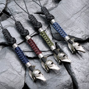 May include: Five keychains with different colored paracord and silver spearhead charms. The keychains are on a gray background.