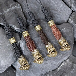 May include: Four keychains with a skull design and a crown. Each keychain has a different colored cord: black, brown, black, and brown. The skull is made of brass and has a detailed design.