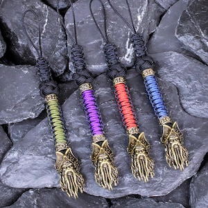 May include: Four keychains with different colored paracord and metal viking head charms. The charms are in shades of gold, green, purple, and blue.