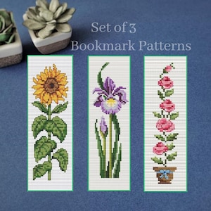 May include: Set of three cross-stitch bookmark patterns featuring a sunflower, iris, and roses. The sunflower has yellow petals and green leaves. The iris is purple and white. The roses are pink and in a pot with a blue bow.