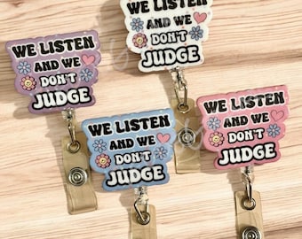 May include: Five colorful badge reels with the text "WE LISTEN AND WE DON'T JUDGE". Each reel has a different color scheme, including purple, white, blue, and pink, with floral and heart accents. The reels have a retractable cord and a belt clip.