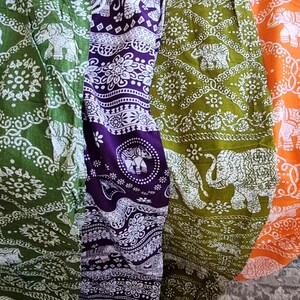 May include: Three pairs of elephant print pants in green, purple, and orange. The pants have a white elephant design on a dark background.
