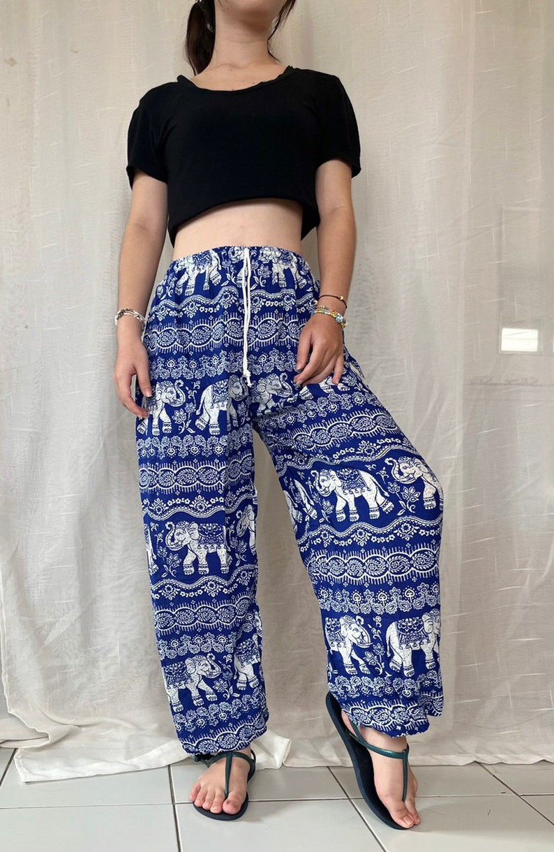 May include: Blue and white printed pants with an elephant design. The pants have an elastic waistband and a drawstring.