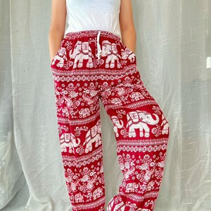 May include: Red pants with a white elephant print. The pants have an elastic waistband and a drawstring. The pants are loose fitting and flowy.