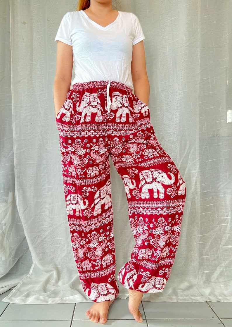 May include: Red pants with a white elephant print. The pants have an elastic waistband and a drawstring. The pants are loose fitting and flowy.