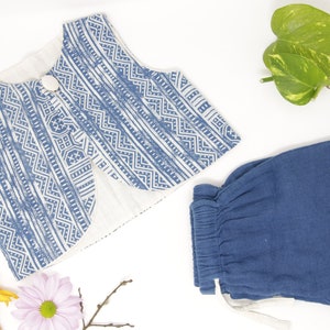 Puede incluir: Un chaleco azul y blanco con estampado y un botón blanco y un par de pantalones cortos azules lisos.