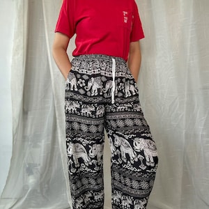 May include: Black and white patterned pants with an elephant design. The pants have an elastic waistband and a drawstring.