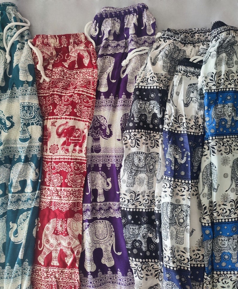 May include: Five pairs of elephant print pants in different colors, including teal, red, purple, black, and white. The pants have an elastic waistband and a drawstring.