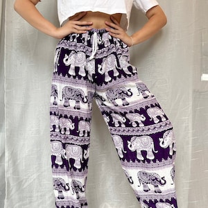 May include: Purple pants with a white elephant print. The pants have an elastic waistband and a drawstring.