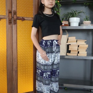 May include: A person wearing a black cropped top and blue and white patterned pants with an elephant design. The pants have a drawstring waist.