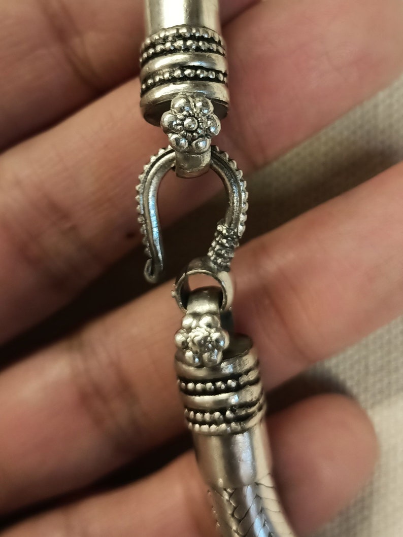 Pu&ograve; includere: Braccialetto in argento con un design floreale dettagliato e una chiusura a gancio.