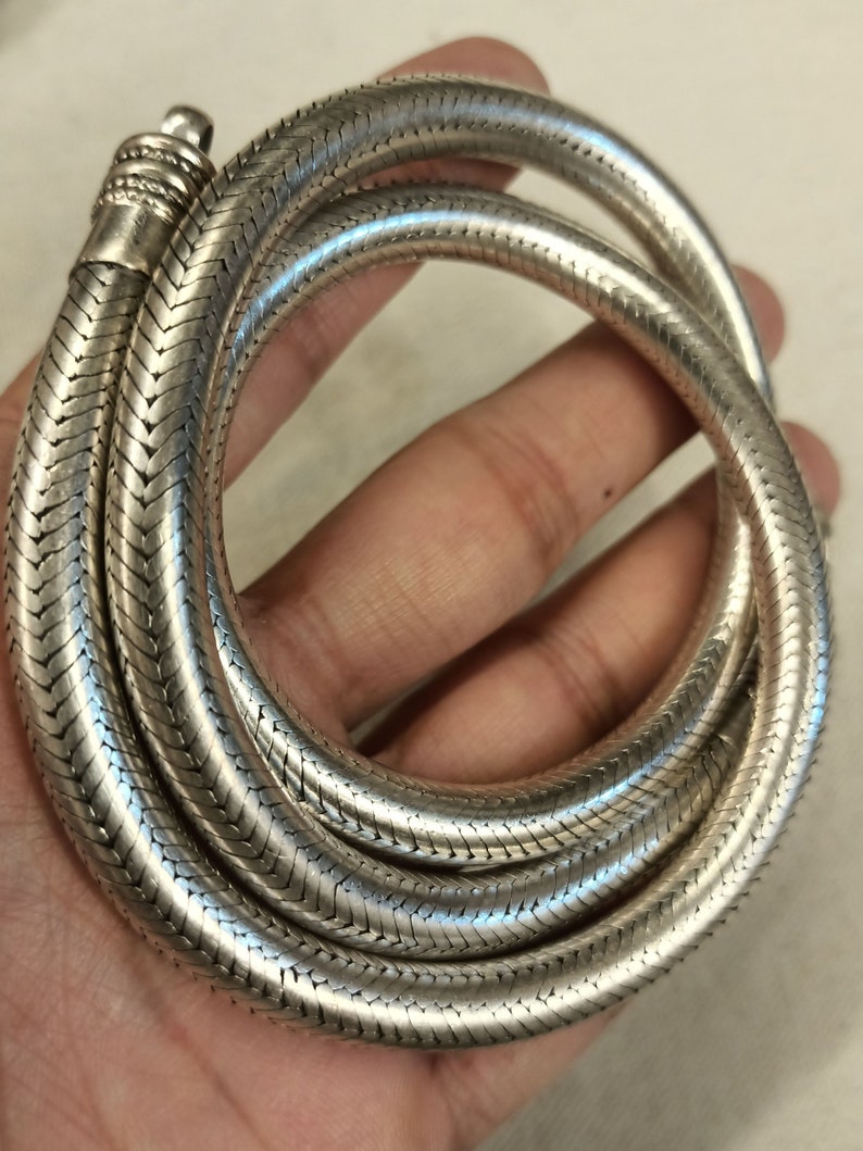 Pu&ograve; includere: Una collana a catena di serpente d'argento con finitura testurizzata. La catena &egrave; avvolta e sembra essere composta da piccoli anelli intrecciati.
