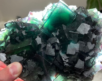 May include: A large green and black fluorite crystal cluster with iridescent facets. The crystal is composed of many smaller crystals that have grown together.
