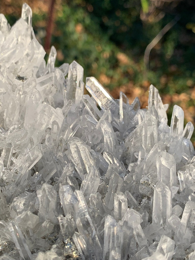 Może przedstawiać: Gromada przezroczystych kryształ&oacute;w kwarcu o szorstkiej, naturalnej fakturze. Kryształy są spiczaste i mają przezroczysty wygląd.