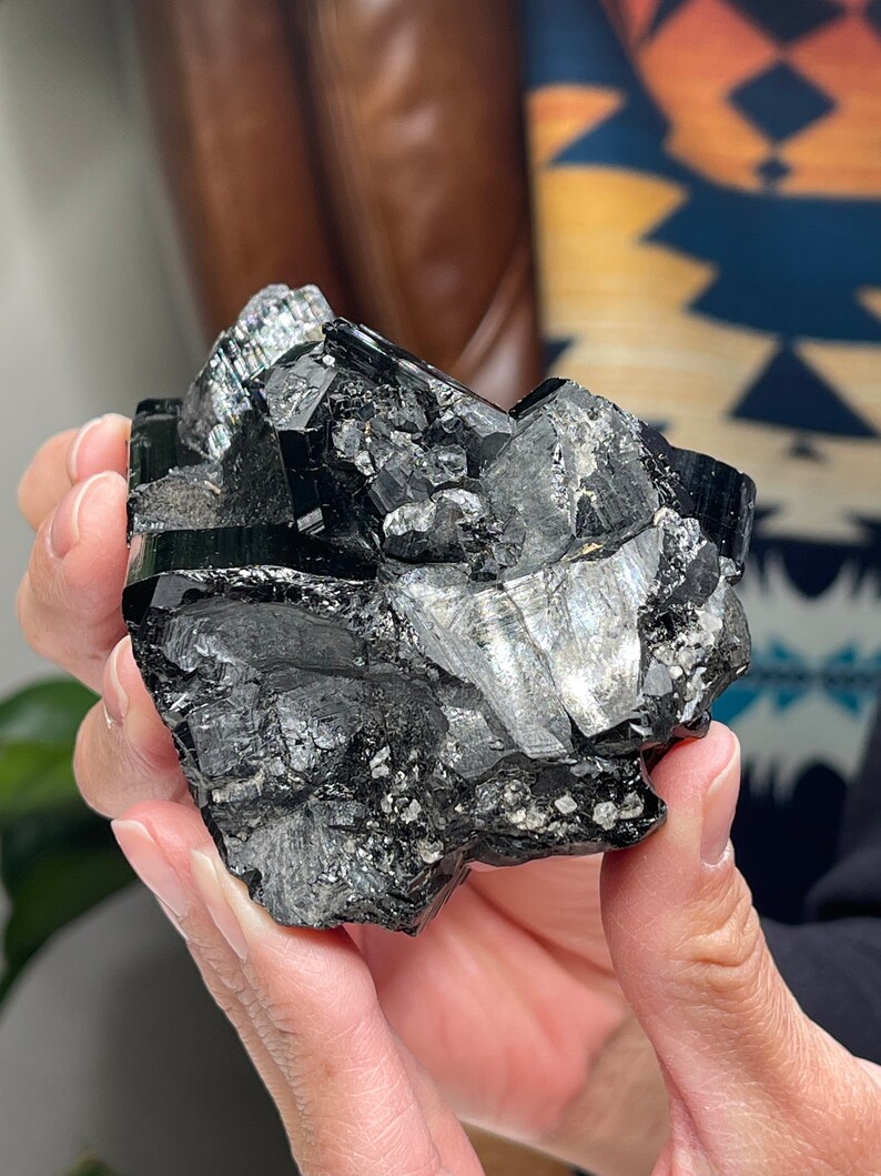 Pu&ograve; includere: Un grande ammasso di cristalli nero e argento con una texture ruvida e naturale. Il cristallo ha una forma angolare e appuntita ed &egrave; composto da pi&ugrave; sfaccettature.