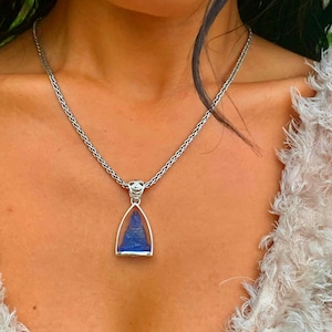 May include: A silver chain necklace with a blue glass pendant featuring a small Buddha statue.