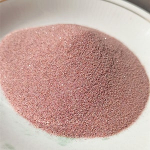 May include: A close-up view of a pile of fine, pink sand. The sand is smooth and uniform in texture, with a slight sheen.