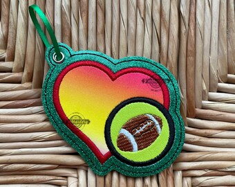 May include: Green glitter heart-shaped ornament with a red heart and a green and brown football inside.