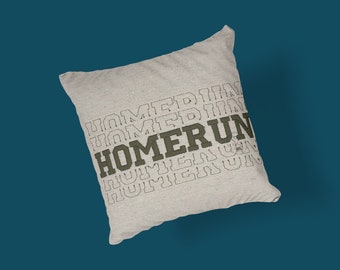 May include: A beige throw pillow with the word "HOMERUN" printed in dark green letters. The word "HOMERUN" is repeated several times in a stacked pattern, with each repetition slightly smaller than the one above it.