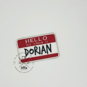 Puede incluir: Etiqueta de nombre roja y blanca con el texto "HELLO my name is DORIAN".