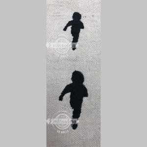 May include: Two black embroidered silhouettes of people walking on a beige fabric background.