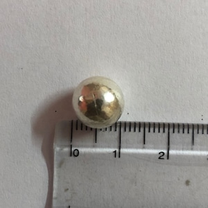 Op de afbeelding: Een zilverkleurige metalen bal met een diameter van ongeveer 1 cm.