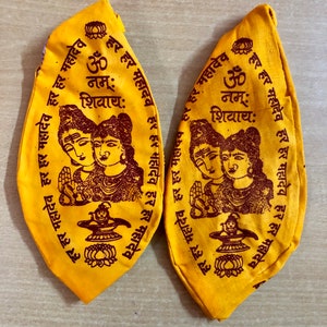 May include: Two yellow fabric pouches with brown printed text and images. The text includes the words "Om Nam: Shivaya" and "Har Har Mahadev". The images depict a couple with a lotus flower and a trident.